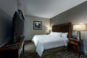 a hotel room with a bed and a flat screen tv at Embassy Suites Saratoga Springs in Saratoga Springs