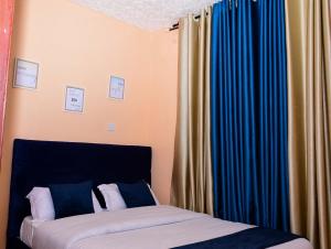 1 dormitorio con 2 camas y cortinas azules en Modern & Homely Suite with Free Parking & WiFi en Embu