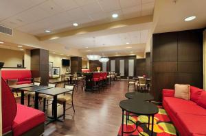 un restaurante con sofás rojos, mesas y sillas en Hampton Inn Jacksonville en Jacksonville