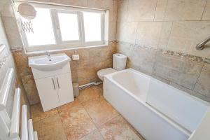 a bathroom with a tub and a toilet and a sink at Seaside double room in cozy house in New Brighton