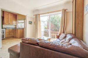 a living room with a brown leather couch in front of a window at Seaside double room in cozy house in New Brighton