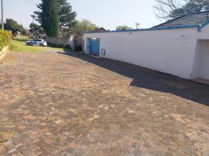 a brick driveway in front of a white building at WAKEUP FRESH GUEST HOUSE in Johannesburg