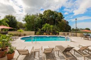a swimming pool with chairs and a table and a fence at Hampton Inn Bonita Springs Naples North in Bonita Springs