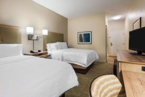 a hotel room with two beds and a flat screen tv at Hampton Inn Bonita Springs Naples North in Bonita Springs