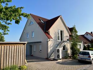 a house with a car parked in the driveway at Tolle Maisonette Wohnung mit Seeblick - Ferienwohnung Seeliebe in Büchelberg