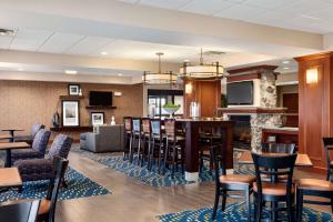 a restaurant with a bar with chairs and tables at Hampton Inn Watertown in Watertown