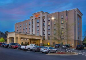 a hotel building with cars parked in a parking lot at Hampton Inn Covington in Covington