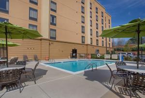 a hotel patio with a pool and tables and umbrellas at Hampton Inn Covington in Covington