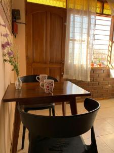 una mesa de madera con dos tazas y un jarrón. en Departamento Privado para dos personas en Mendoza en Godoy Cruz