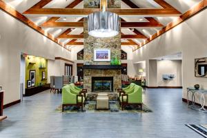un vestíbulo con chimenea de piedra y sillas verdes en Hampton Inn & Suites Atlanta/Duluth/Gwinnett, en Duluth