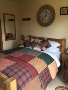 1 dormitorio con 1 cama con reloj en la pared en Bumbleberry Cottage, en Gresford