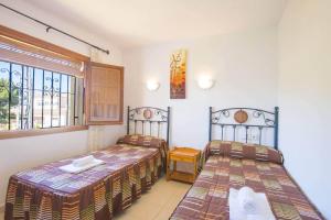 een slaapkamer met 2 bedden en een raam bij Villa Cactus - PlusHolidays in Calpe