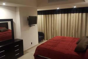 a bedroom with a red bed and a television at Grand Venetian - Zen oceanview condo in hotel zone in Puerto Vallarta +21 photos