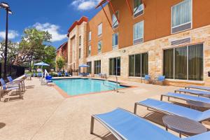 a swimming pool with chairs and a building at Hampton Inn Austin Oak Hill in Austin