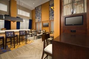 a restaurant with tables and chairs and a flat screen tv at Hampton Inn & Suites Baltimore/Woodlawn in Baltimore