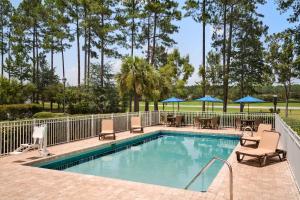 una piscina con sillas, mesas y sombrillas en Hampton Inn & Suites Bluffton-Sun City, en Bluffton