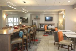 a restaurant with a bar and tables and chairs at Hampton Inn Owego in Owego