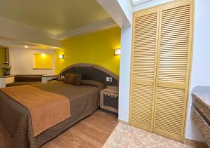 - une chambre avec un lit et un mur jaune dans l'établissement Hotel Villa de Madrid, à Mexico