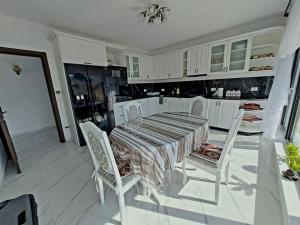 a white kitchen with a table and white chairs at Conacul Munții Bucovinei in Câmpulung Moldovenesc