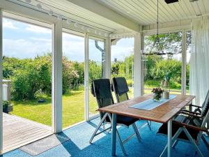 a screened in porch with a wooden table and chairs at 7 person holiday home in KöPINGSVIK-By Traum in Köpingsvik