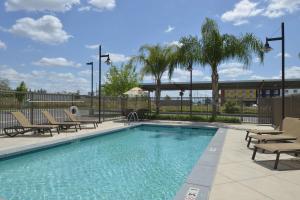 a swimming pool with chaises and chairs next to a fence at Hampton Inn and Suites Bakersfield North-Airport in Bakersfield
