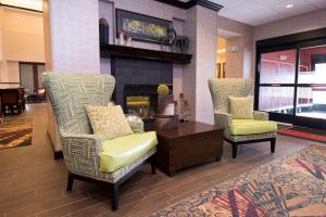 vestíbulo con 2 sillas, mesa y chimenea en Hampton Inn & Suites Bismarck Northwest, en Bismarck