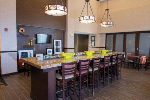 a large bar with a row of stools in a restaurant at Hampton Inn & Suites Bismarck Northwest in Bismarck