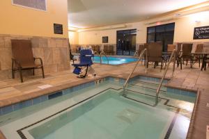 uma piscina num hotel com cadeiras e uma mesa em Hampton Inn & Suites Bismarck Northwest em Bismarck