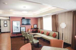 a hotel room with a couch and tables and chairs at Hampton Inn Bloomington West in Bloomington