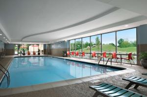 a large swimming pool with red chairs and tables at Home2 Suites Nashville Airport in Nashville