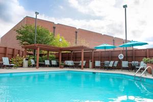 a swimming pool with chairs and umbrellas next to a building at Hampton Inn & Suites Nashville-Green Hills in Nashville
