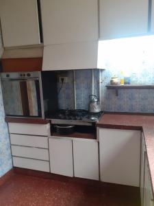 a small kitchen with a stove and white cabinets at Habitación en peatonal de Concordia 25000 PESOS LA NOCHE in Concordia