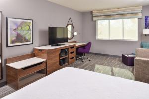 a hotel room with a bed and a desk with a mirror at Hampton Inn & Suites Boise/Spectrum in Boise