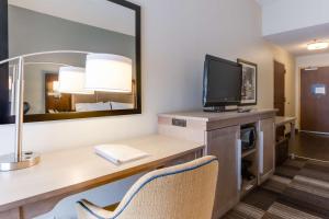 a hotel room with a desk with a tv and a mirror at Hampton Inn Bellevue/Nashville I-40 West in Bellevue