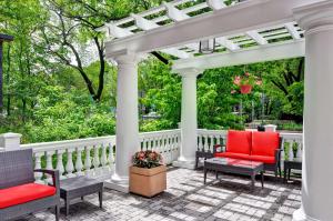 une pergola blanche avec des chaises rouges sur une terrasse dans l'établissement Homewood Suites by Hilton Boston Cambridge-Arlington, MA, à Arlington