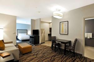 um quarto de hotel com uma secretária e um quarto com uma cama em Homewood Suites by Hilton Boston Cambridge-Arlington, MA em Arlington