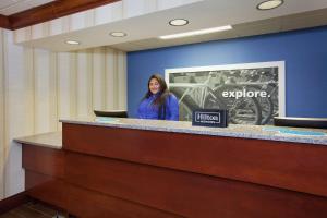 a woman is standing behind a reception desk at Hampton Inn Boston / Marlborough in Marlborough