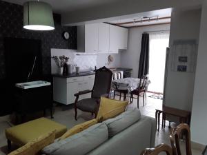 a living room with a white couch and a kitchen at LE DOMAINE DU HIBOU 