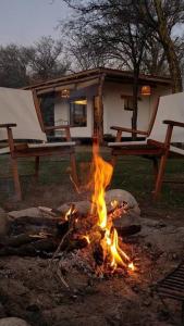a fire pit in front of a house with two chairs at Hospedaje Sauce Linda - Casa Brea in Piedra Pintada