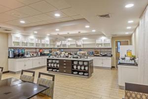 a large kitchen with white cabinets and tables and chairs at Homewood Suites by Hilton Brownsville in Brownsville
