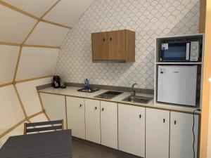 a kitchen with white cabinets and a microwave and a refrigerator at GLAMPING DO MAR in Baiona