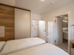 1 dormitorio con cama blanca y puertas correderas en Herzi Chalet - top ausgestattet, neu, chic und sehr gemütlich, en Walchsee