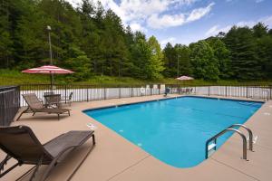 a swimming pool with chairs and umbrellas on a patio at Hampton Inn Brevard in Pisgah Forest