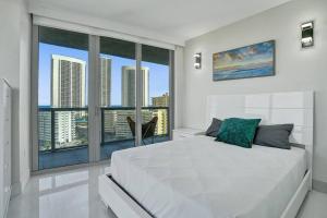 a bedroom with a white bed and a large window at Gorgeous 4 BDRM Condo Stunning Views Beach Access in Hallandale Beach