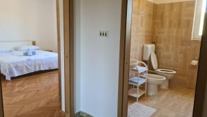 a small bathroom with a bed and a toilet at Apartman Lana in Vir