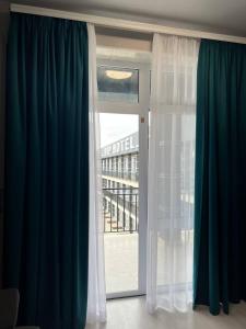 Habitación con cortinas azules y blancas y ventana en VIP HOTEL ZATOKA en Zatoka