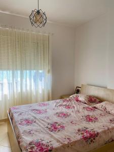 um quarto com uma cama grande com flores cor-de-rosa em Eden Home em Durrës