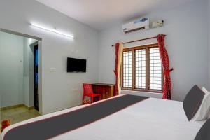 1 dormitorio con 1 cama, TV y ventana en OYO B&B Rooms en Kollam