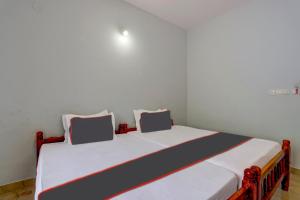 1 dormitorio con 1 cama blanca grande y 2 almohadas en OYO B&B Rooms en Kollam