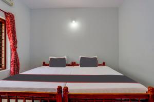een slaapkamer met een bed met 2 stoelen naast een raam bij OYO B&B Rooms in Kollam